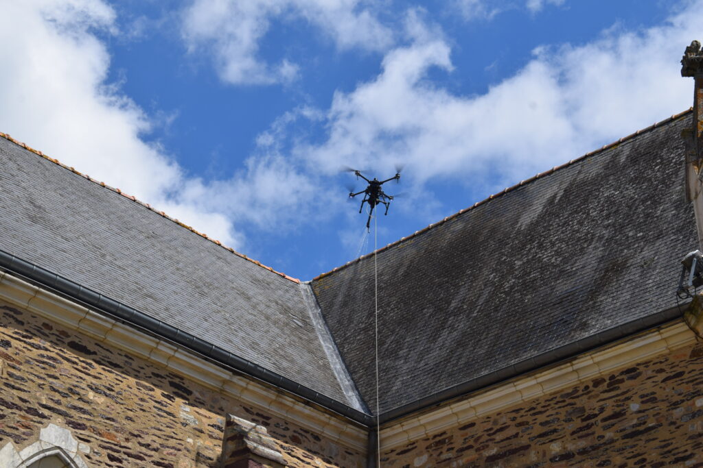 Drone réalisant le nettoyage d'une toiture en ardoise