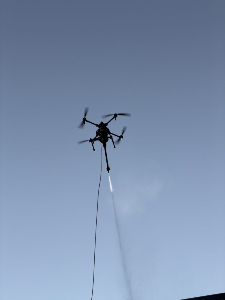 Drone réalisant une pulvérisation aérienne sur un bâtiment