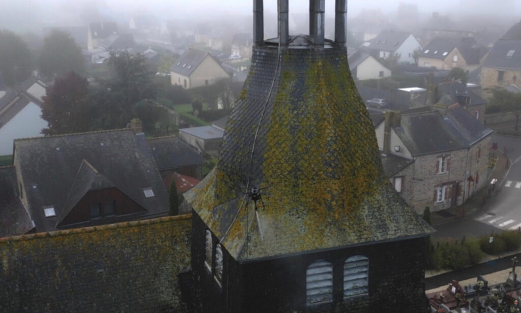 Drone réalisant un traitement sur le clocher en ardoise d'une église