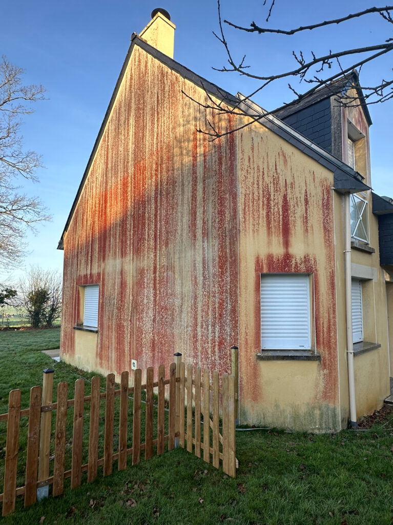 Façade de maison marquée par des traces rouges avant nettoyage par drone