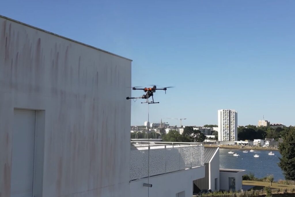 Drone réalisant le nettoyage d'une façade d'immeuble à Lorient grâce à la technologie Dropdrone