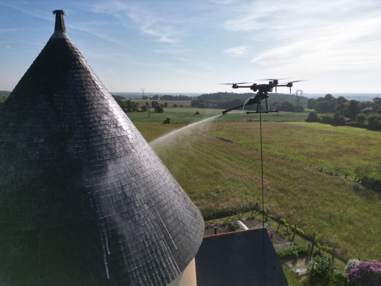 Drone Dropdrone réalisant le nettoyage d'une toiture de maison individuelle