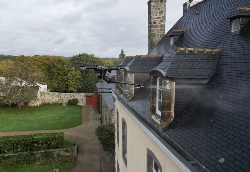 Drone Dropdrone appliquant un traitement hydrofuge sur la toiture en ardoise d’un manoir en Bretagne