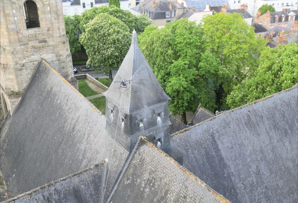 Drone en intervention pour le traitement de la toiture d'une église et d'un bâtiment patrimonial